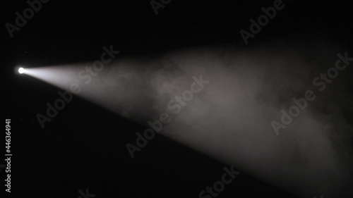 Close-up of a white spotlight shining on the stage in the dark. photo