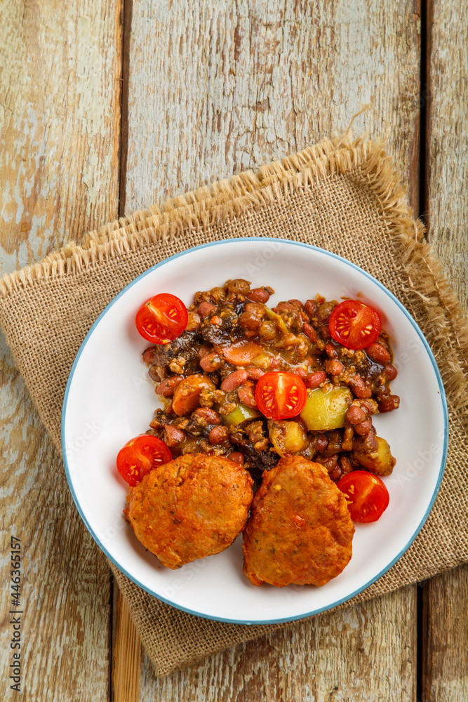 Cod cutlets with stewed potatoes and vegetables on a plate on a napkin on the table. Cod cutlets with stewed potatoes and vegetables on a plate on a napkin on the table.