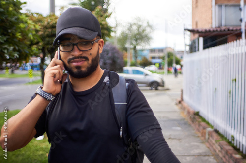 a young dark-haired man talking on a cell phone in the street