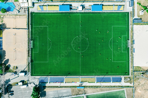 sport center during training of the football team. players are playing a soccer match. aerial top view in summer day.