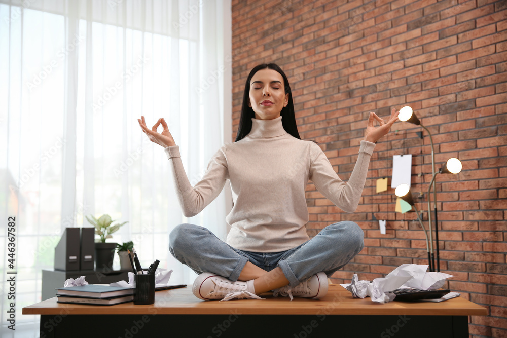 Young woman meditating at workplace. Stress relief exercise Young woman meditating at workplace. Stress relief exercise