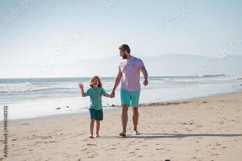 Father and son walking on sea. Dad and child holding hands and walk together.