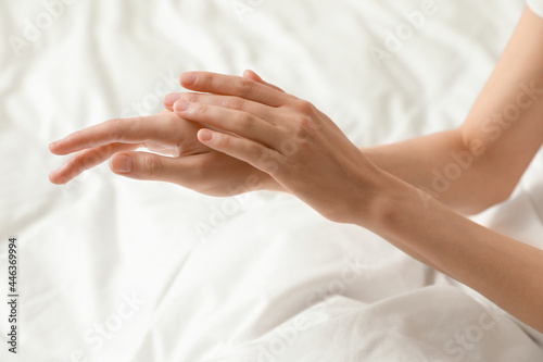 Woman applying hand cream in bed  closeup