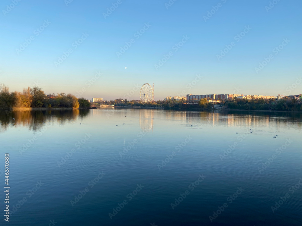 Fototapeta premium Lake with city reflection on sunset landscape view of