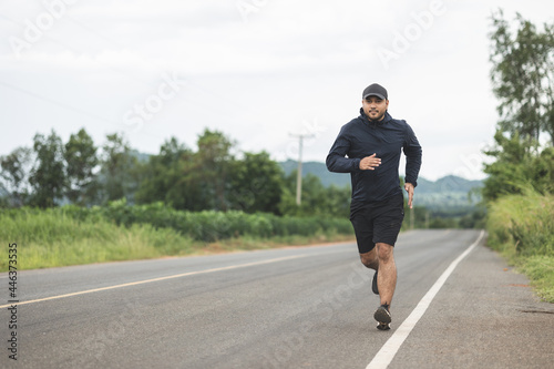 Asia man wearing sportswear running on the road with mountain background. Young man jogging for exercise in the nature. healthy lifestyle and sports concept