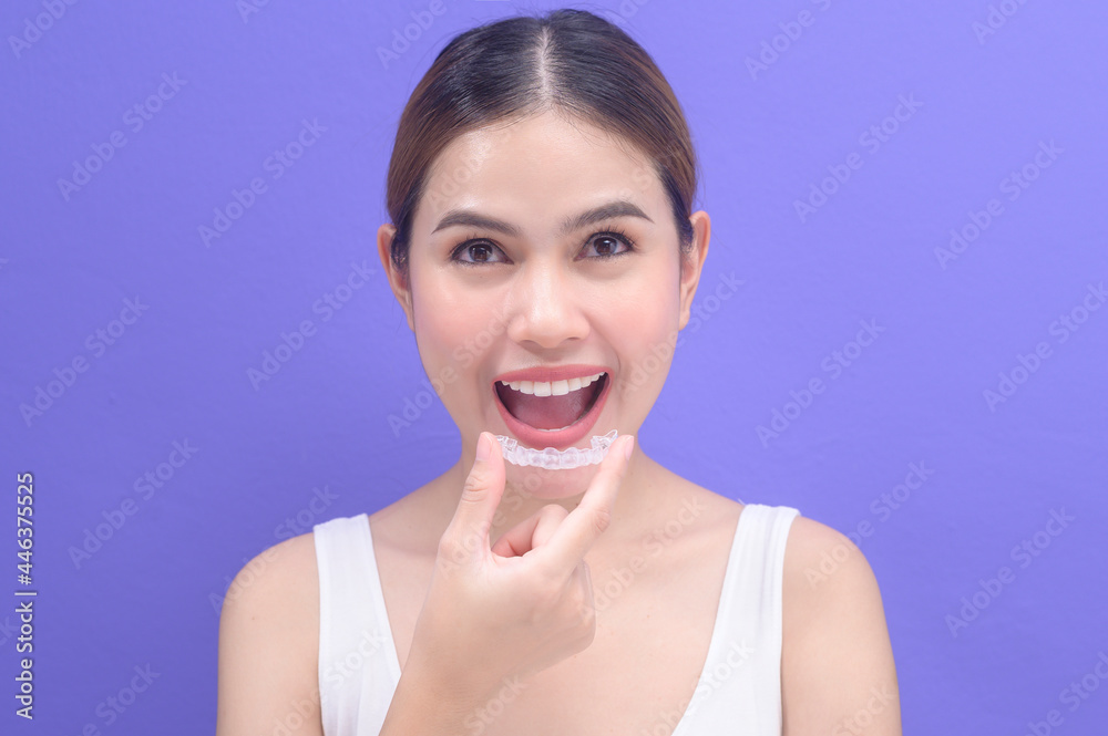 Young smiling woman holding invisalign braces in studio, dental healthcare and Orthodontic concept.. Young smiling woman holding invisalign braces in studio, dental healthcare and Orthodontic concept..