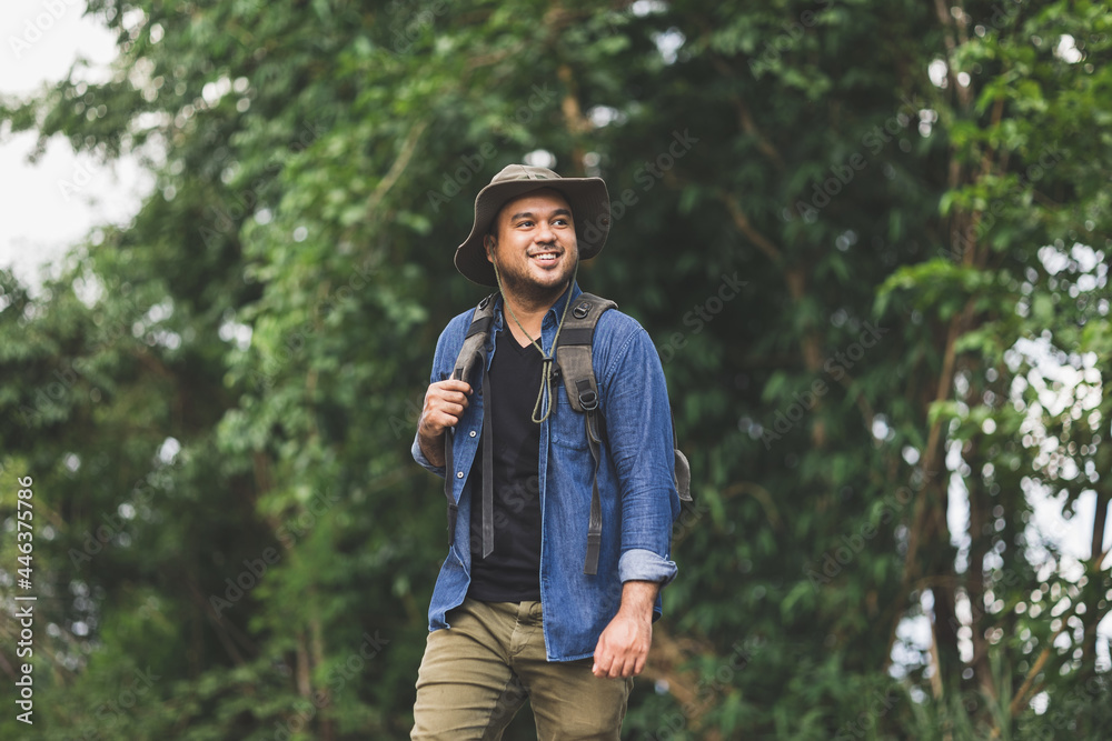 Young handsome man with a backpack is walking alone the road. Man is looking forward to an interesting travelling.