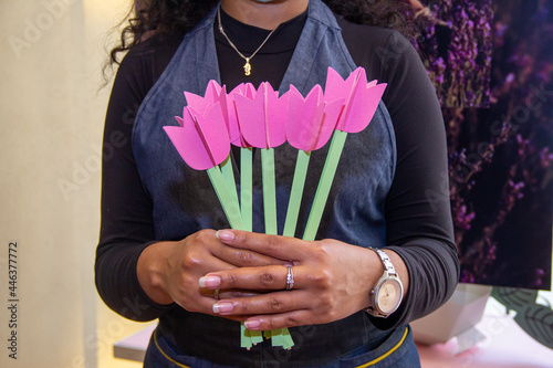 chica sostiene arrelgo de flores hechas de papel, decoracion manual de flores photo
