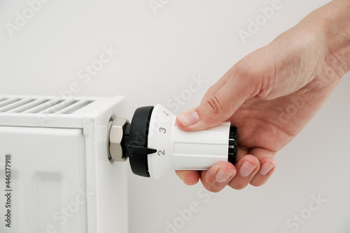 Heat radiator knob. Woman hand adjusting temperature on heating radiator