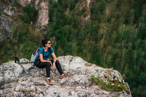 Hiking in the mountains. A trip to the mountains. Tourist in the mountains. Active leisure time concept. Traveling woman with a backpack on the background of mountains. Happy girl traveler. Copy space