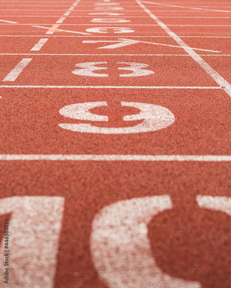Fototapeta premium Sideview on lane numbers at the finish of red race track (running track or athletics track), shallow depth of field