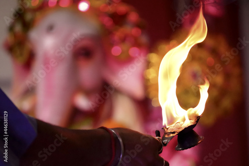 Close-up of a priest offering sacred flame to an idol of the god Ganesha