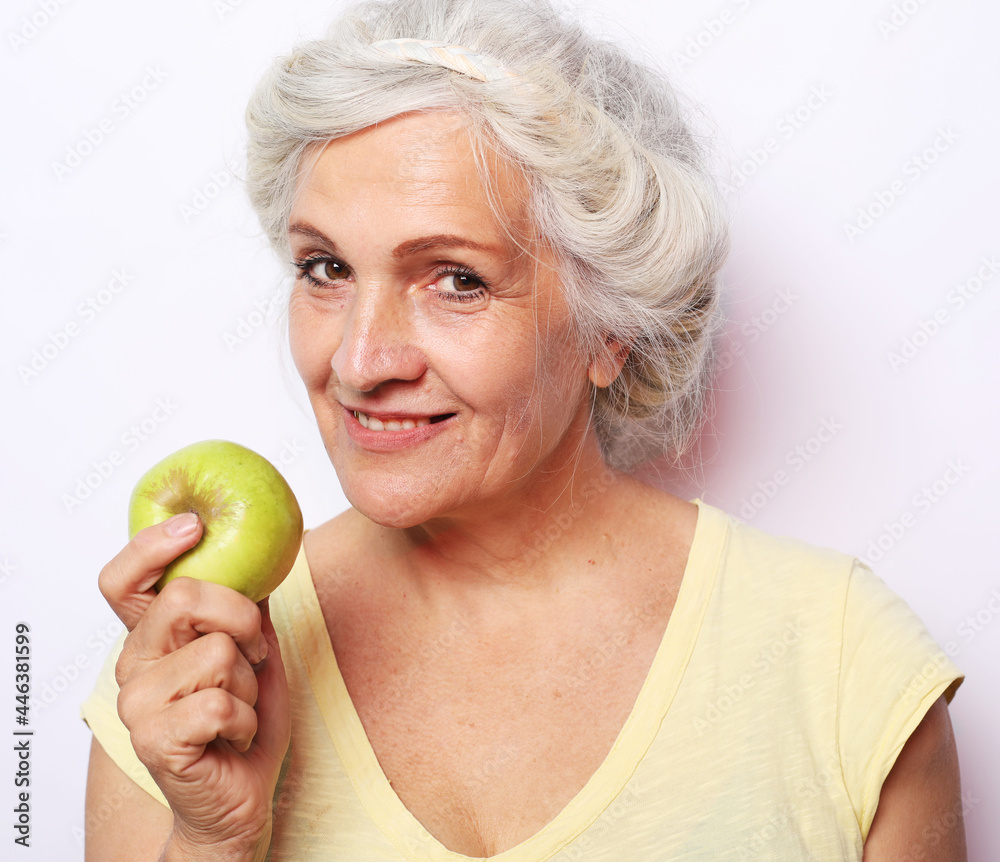 Portrait of a beautiful elderly woman holding an apple, smiling, isolated on white background. Portrait of a beautiful elderly woman holding an apple, smiling, isolated on white background.