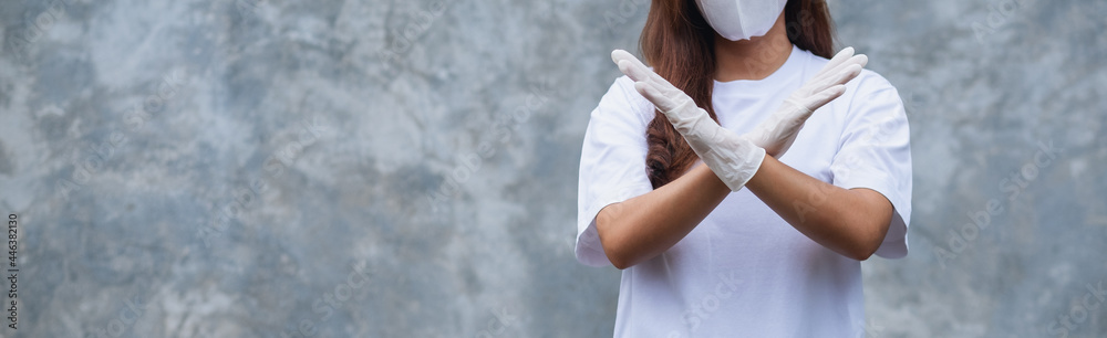 Closeup image of a woman wearing protective face mask and medical rubber gloves making crossed arms or stop hand sign for Health care and Covid-19 concept Closeup image of a woman wearing protective face mask and medical rubber gloves making crossed arms or stop hand sign for Health care and Covid-19 concept