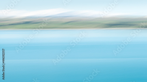 Abstract image of turquoise colours of Lake Pukaki with snow-capped mountains in the distance. Image taken by intentional camera movement. South Island.