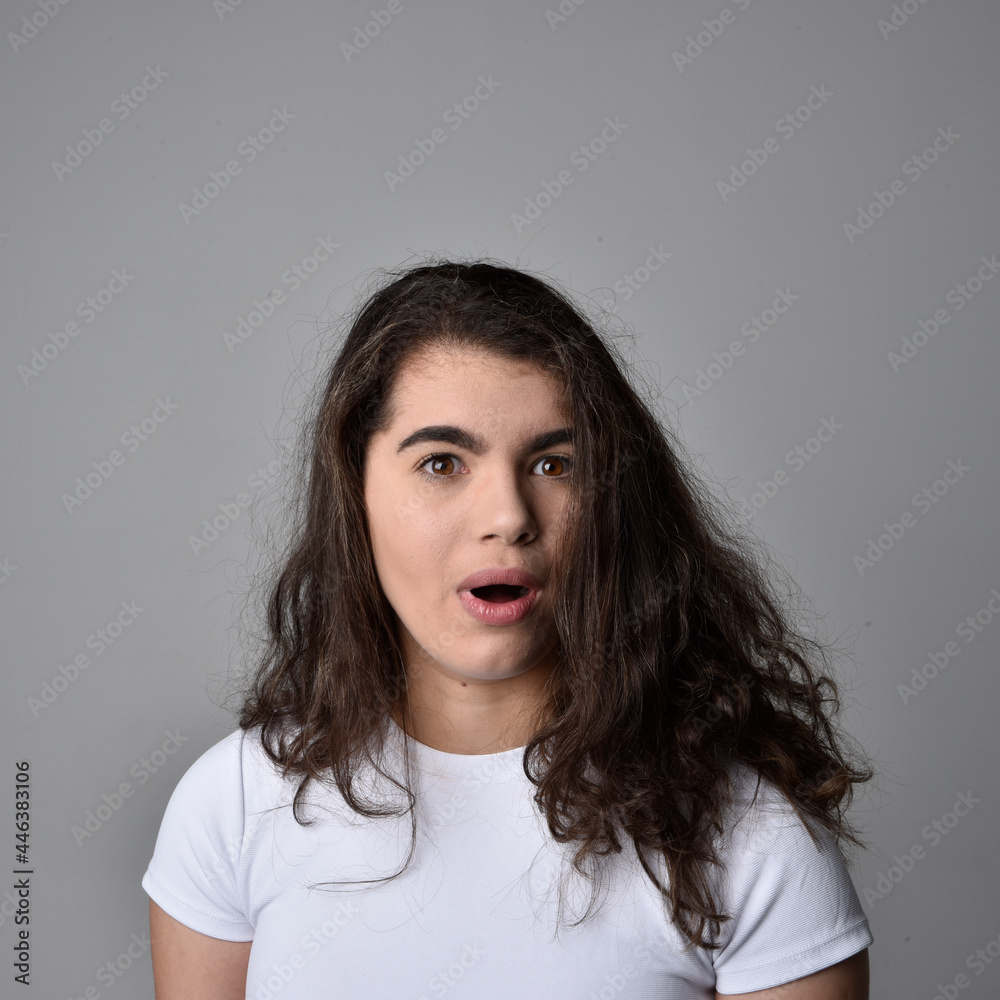 Close up portrait of young woman with natural brown hair, over the top facial expressions on light grey studio background. Close up portrait of young woman with natural brown hair, over the top facial expressions on light grey studio background.