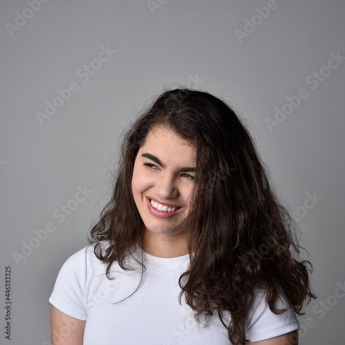 Close up portrait of young woman with natural brown hair  over the top facial expressions on light grey studio background.