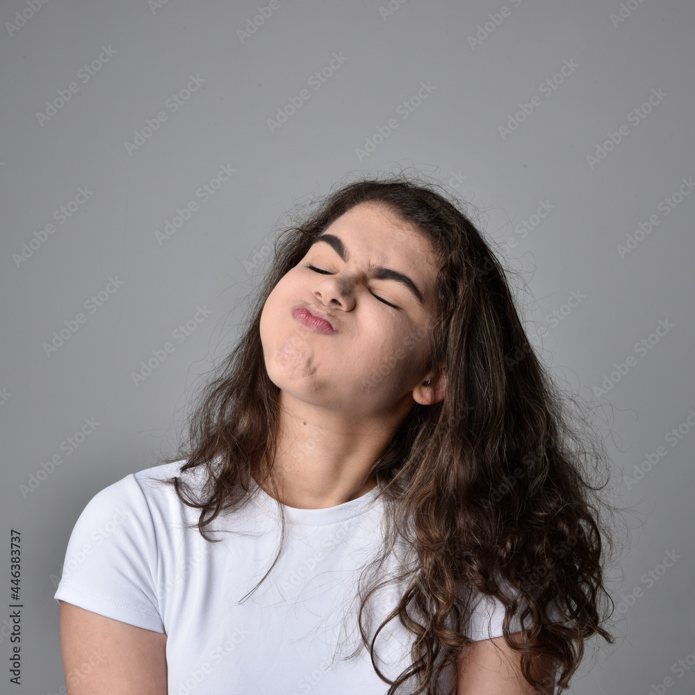 Close up portrait of young woman with natural brown hair, over the top facial expressions on light grey studio background. Close up portrait of young woman with natural brown hair, over the top facial expressions on light grey studio background.