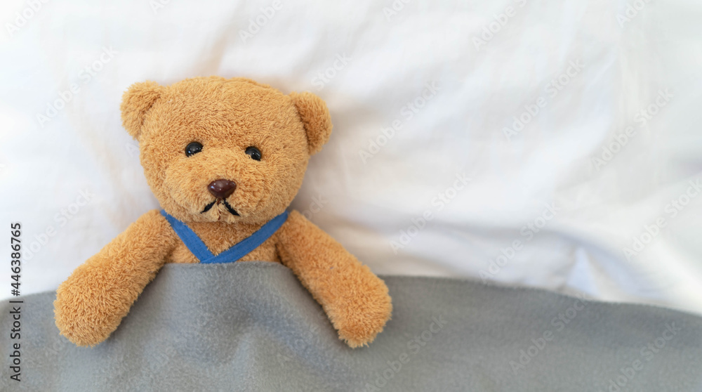 Sad and disappointed teddy bear lying in bed. Teddy bear is sick and crying.