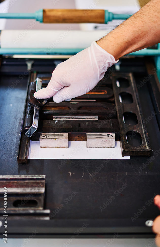 Crop worker making imprint with letterpress font in typography Crop worker making imprint with letterpress font in typography