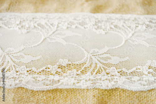 Gros-plan d'une dentelle d'un chemin de table blanc sur un tissu en lin beige
