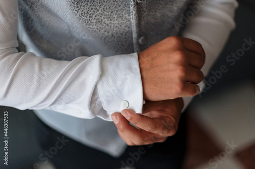 Stylish man in elegant outfit buttoning cuff on shirt