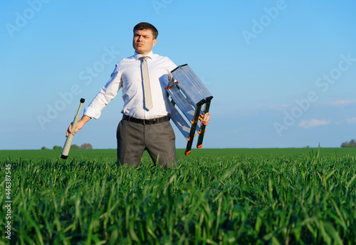 businessman poses with a spyglass in a green field, he looks an idea or something, business concept, green grass and blue sky as background
