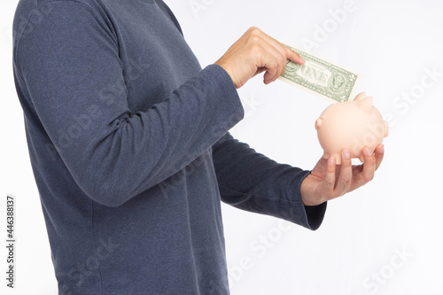 A man holding pink piggy bank and put dollar banknote for saving, COVID-19 concept