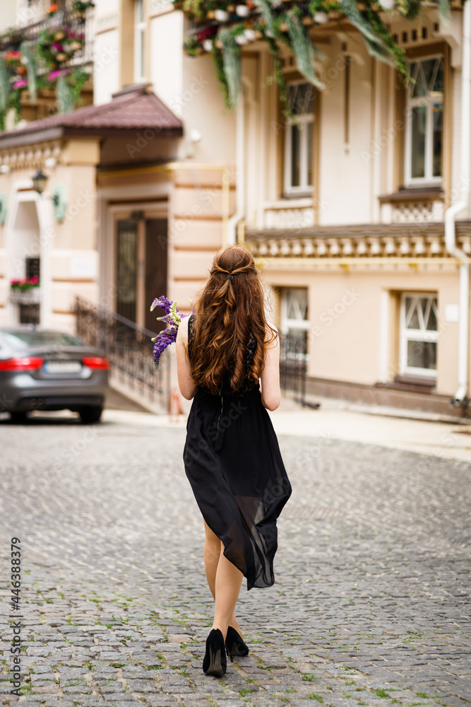 girl in a black dress with purple flowers in the city