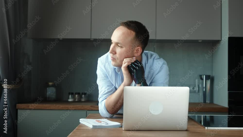 Manager man with bio hand prothesis sits at table with notes Manager man with bio hand prothesis sits at table with notes