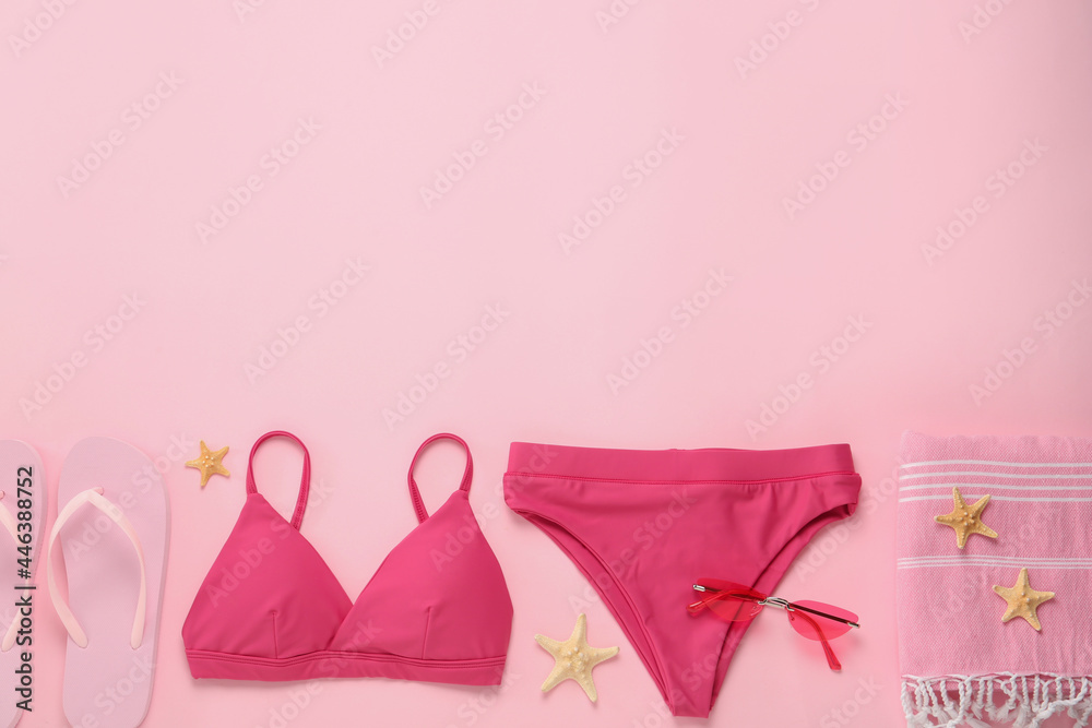 Stylish bikini and beach accessories on pink background, flat lay. Space for text