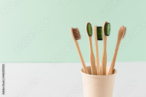 Eco friendly bamboo toothbrushes over green wall. Zero waste hygiene products concept.