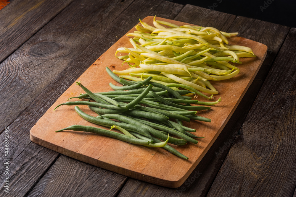 Green and yellow bean pods on rustic wooden table. Freshly harvested raw beans on wooden desk. Green and yellow bean pods on rustic wooden table. Freshly harvested raw beans on wooden desk.