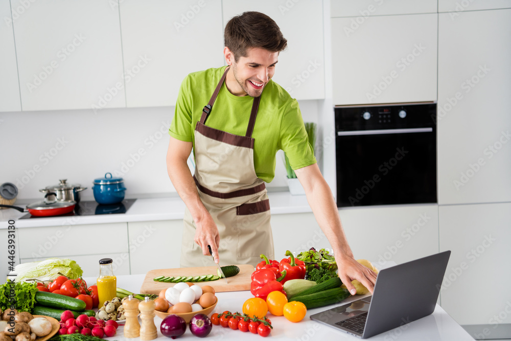 Portrait of attractive cheerful guy cooking fresh meal dish watching video web learning at home kitchen indoors Portrait of attractive cheerful guy cooking fresh meal dish watching video web learning at home kitchen indoors
