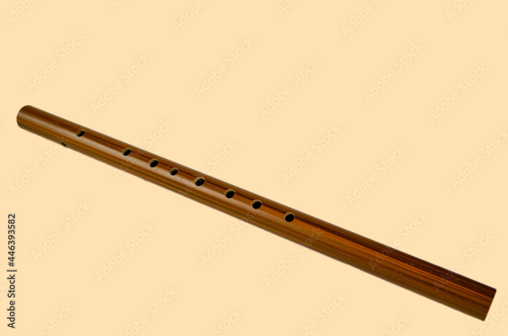 Brown bamboo flute instrument isolated on a soft yellow background. Brown bamboo flute instrument isolated on a soft yellow background.