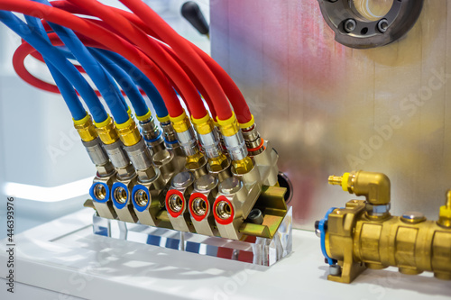 Hydraulic high pressure hoses and valves on mold control system of cooling with red and blue tubes - part of automatic injection molding machine