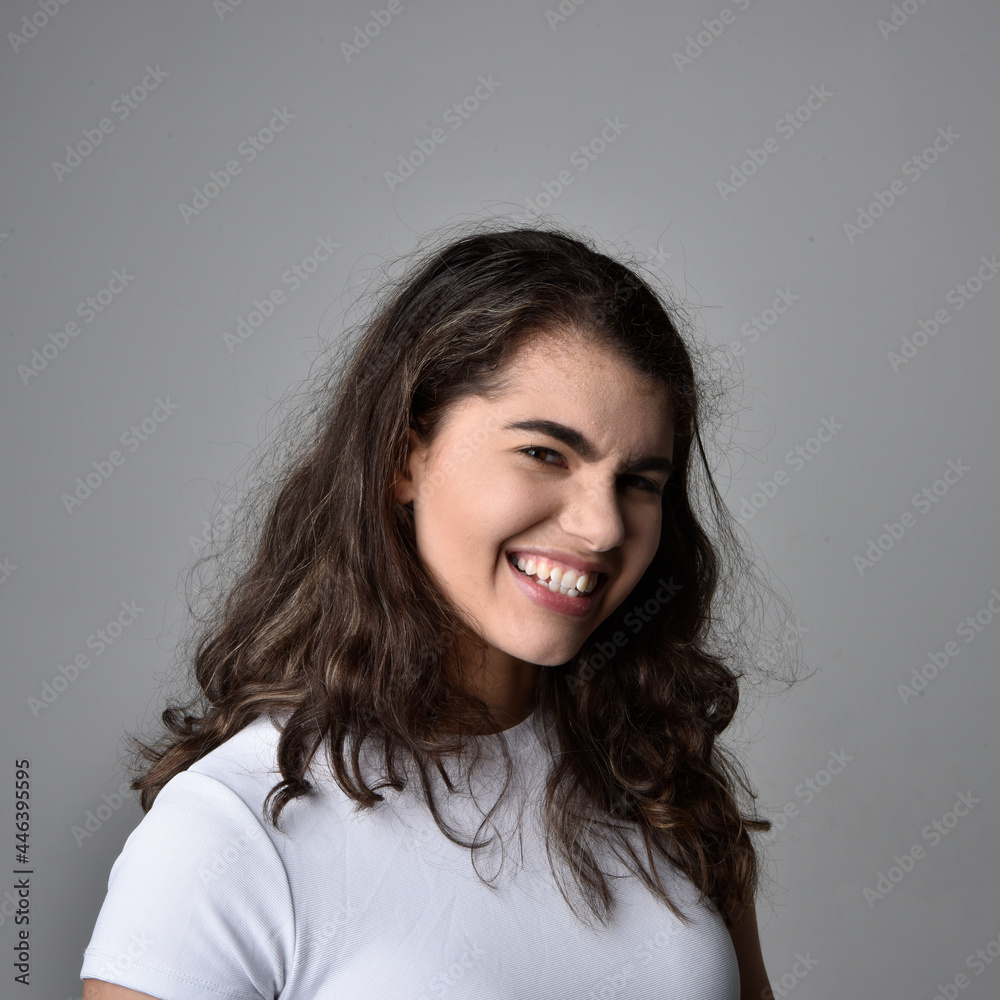 Close up portrait of young woman with natural brown hair, over the top facial expressions on light grey studio background. Close up portrait of young woman with natural brown hair, over the top facial expressions on light grey studio background.