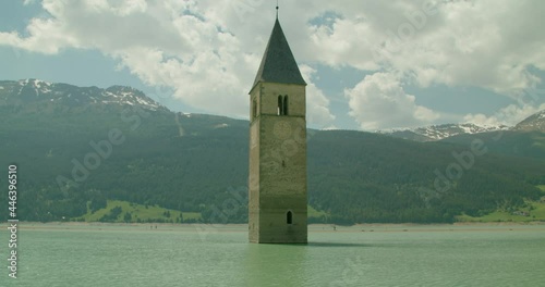 Full shot, Scenic view of Kirchturm von Altgraun clock tower near the shore in Italy, People walking in the background. photo