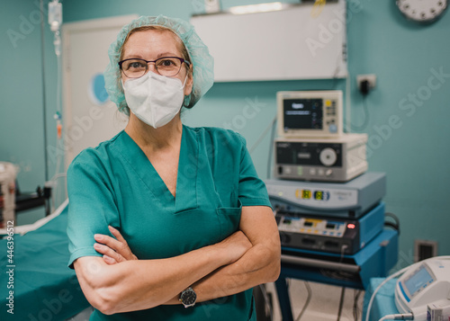 Portrait of female nurse looking at camera inside operating theater at private clinic - Focus on woman face