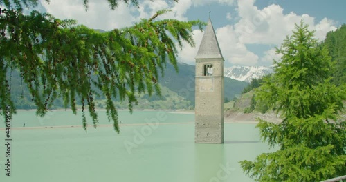 Close up shot, Tree branch blow by the wind in Italy, Kirchturm von Altgraun and People walking on the sun bar on a bright sunny day in the background. photo