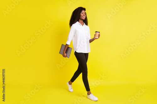 Full size profile photo of young business lady go with tea laptop wear white shirt pants isolated on yellow color background