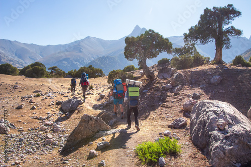 Obraz na płótnie Group hiking in mountains. Group tourists climb the path to the top. Journey with the backpack. w salonie
