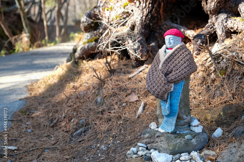 Close up Jizo bosatsu gravestones Japanese little statues known as Jizo or the honorific wear redknit cap along pathway in Sainokawara Park hot spring in Kusatsu Onsen,Japan. photo