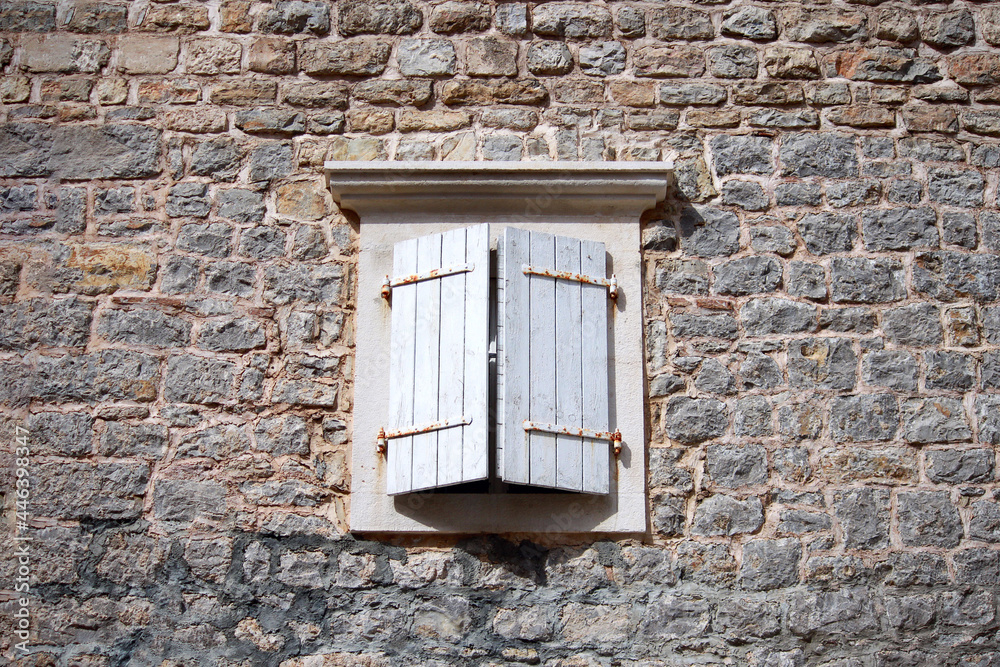 Obraz premium Old wooden window with white shutters of an mediterranean house, vintage background