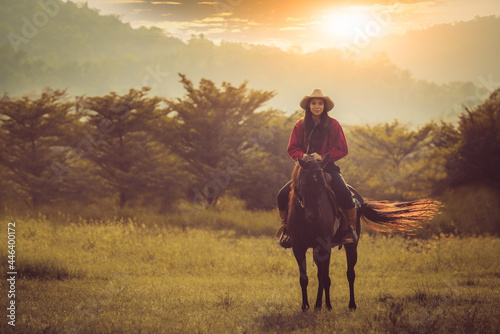Cowgirl horseback riding at summer day with sunlight ray sky background