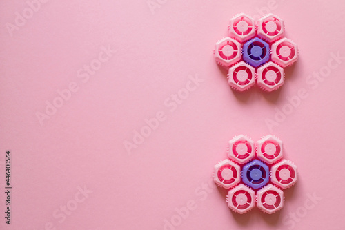 Plastic lids from baby puree in the form of a flower on a pink background. Ecology, copy space