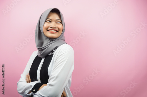 Beautiful young asian muslim woman confident and cheerful looking empty space presenting something, isolated on pink background