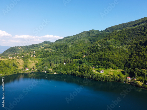 Aerial drone view of lake surrounded by forest in summer. 