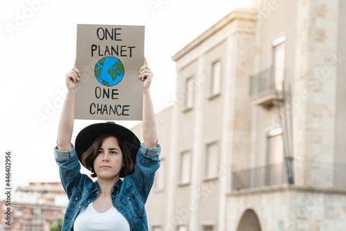 Young demonstrator activist holding banner during climate change protest outdoor in the city - Global warming, environment concept - Focus on hipster girl face