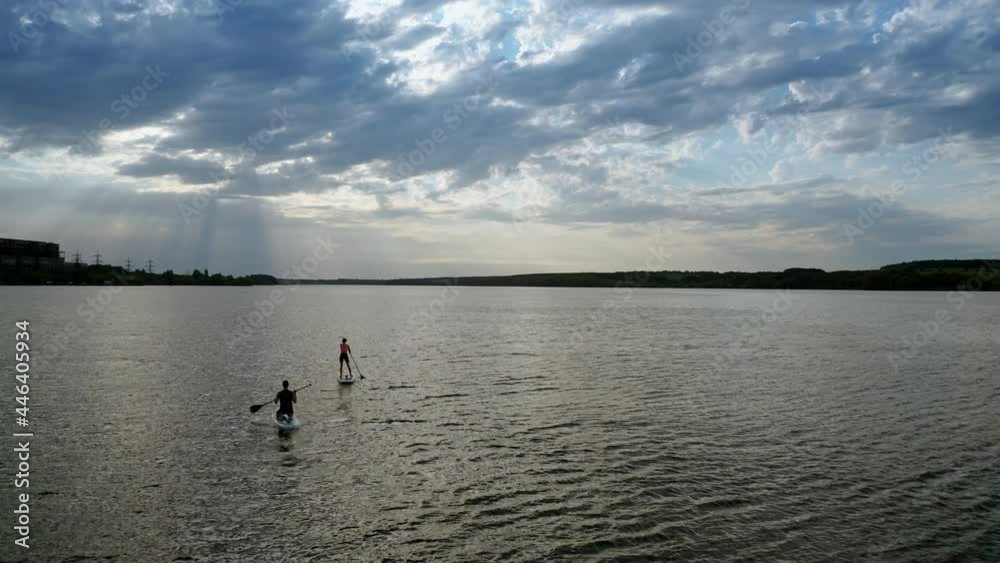 Sporty couple during vacation. Couple standing firmly on inflatable SUP board and paddling Sporty couple during vacation. Couple standing firmly on inflatable SUP board and paddling